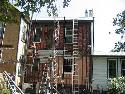 removed siding shows dirty fiberglass insulation showing where air has flowed THROUGH the insulation - GET AN AIR BARRIER